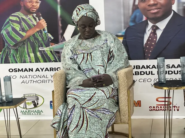 Seated at a community event in a patterned outfit